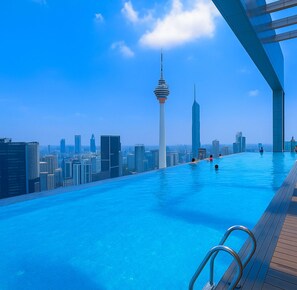 Una piscina infinita con vistas a un horizonte urbano, incluyendo una torre destacada.