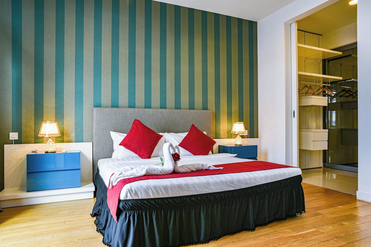 Ein Hotelzimmer mit einem großen Bett, zwei Nachttischen, einem Kleiderschrank und einem Spiegel.