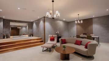 A modern living room with a sofa, a chair, a coffee table, and a dining area.