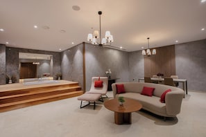 A modern living room with a sofa, a chair, a coffee table, and a dining area.