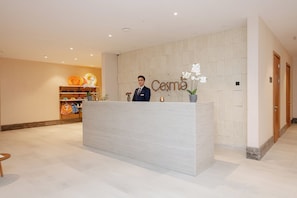 A reception desk with a sign that reads 'Cosmo' and a man standing behind it. - Lachin Resort & SPA (Lachin)