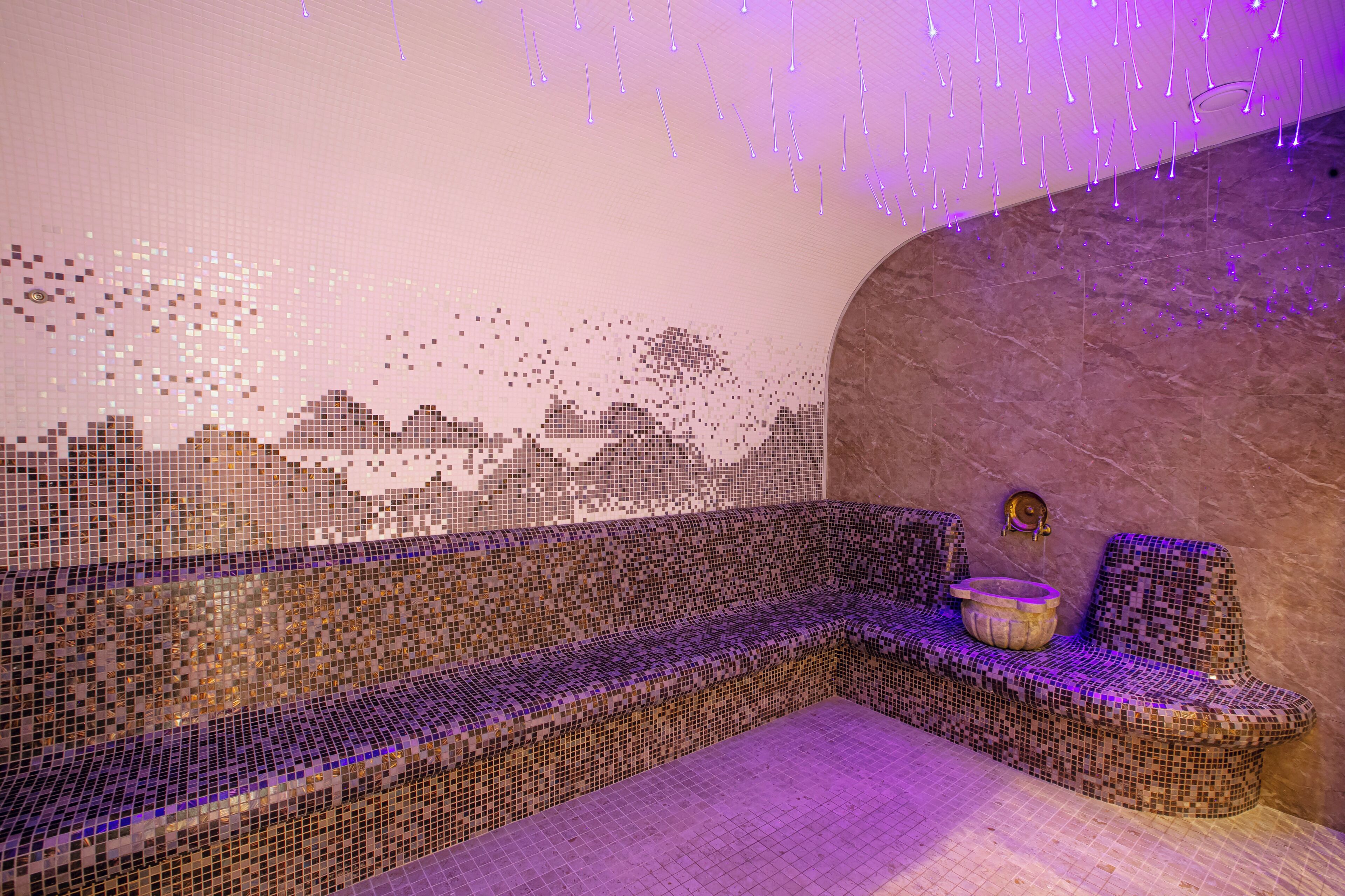 A mosaic-tiled bench with a stone wall and a small basin.