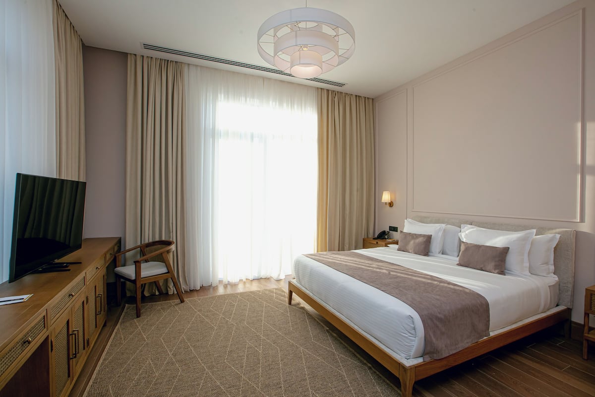 A hotel room with a bed, a television, a desk, and a chair.