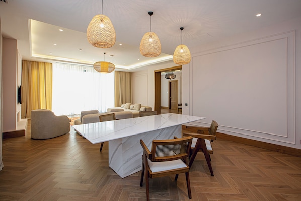 A modern hotel room with a large marble island, wooden chairs, a sofa, and a dining table. - Lachin Resort & SPA (Lachin)