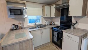 A compact kitchen with a microwave, stove, sink, and cabinets.