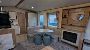 A compact RV interior with a kitchenette, seating area, and a fireplace.