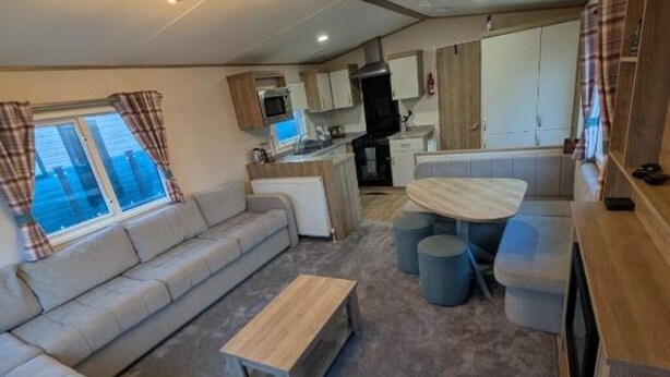 A compact living space with a sofa, a small wooden table, a kitchenette, and a dining area with stools.