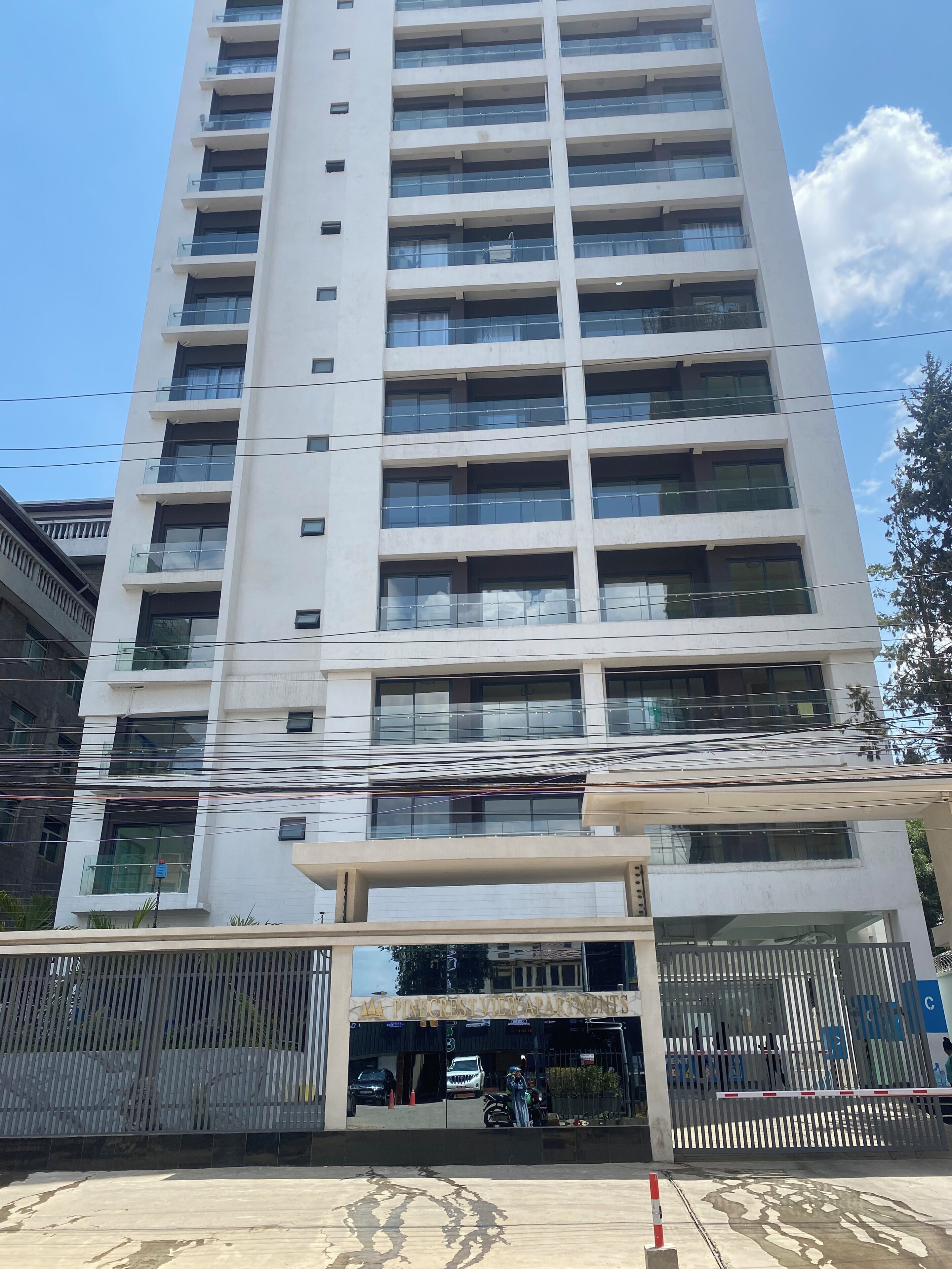 Un edificio de varios pisos con balcones, una entrada con portón y cielo despejado.