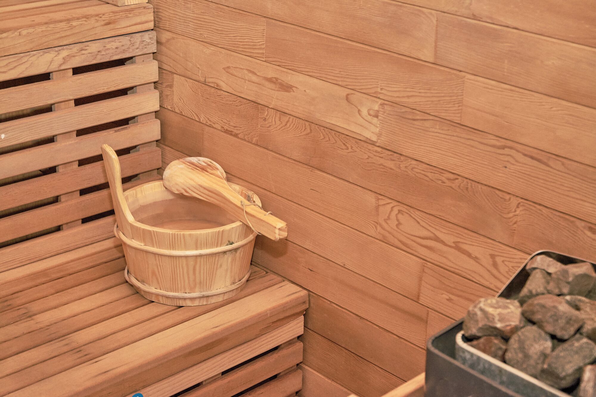Eine Holzausstattung in der Sauna: ein Holzeimer und ein Holzlöffel.