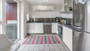 Une cuisine moderne dotée d’appareils électroménagers en acier inoxydable, de meubles blancs et d’un tapis à rayures.