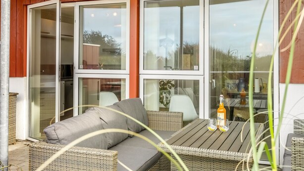 Un patio couvert aménagé avec des meubles en osier, une table et deux chaises.