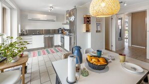 Une cuisine moderne avec des meubles blancs, des appareils en acier inoxydable et un coin repas avec une table mise pour deux personnes.