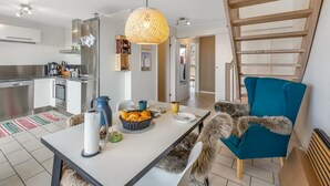 Une cuisine moderne avec un coin repas, un escalier et une vue sur l’extérieur.