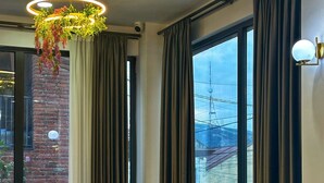 A modern dining area with round tables, green chairs, and a hanging plant chandelier. - BRB Hotel (Tbilisi)