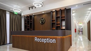 A reception desk with a wooden finish and a sign that reads "Reception". - BRB Hotel (Tbilisi)