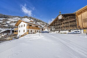 Een besneeuwd dorp met houten gebouwen, waaronder een huis met balkon en een gebouw in aanbouw.