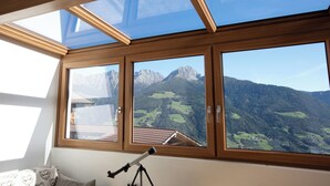 Une pièce dotée d’une lucarne, d’un télescope et offrant une vue sur les montagnes.