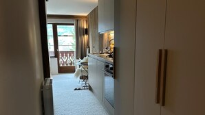 A narrow hallway leading to a kitchen with a dining area. - Alpine cocoon in Megève - charm, comfort & view (Megève)