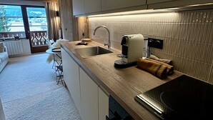 A modern kitchen with a wooden countertop, a built-in stove, and a large window offering a view of the outdoors. - Alpine cocoon in Megève - charm, comfort & view (Megève)