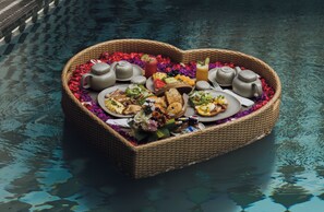 A heart-shaped basket filled with food and drinks on a reflective surface. - Palmea Villa Seminyak by Ini Vie Hospitality (Seminyak)