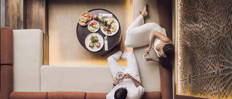A modern interior with a dining area, a sofa, and a decorative wall.