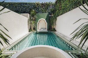 A pool with a geometric tile pattern, surrounded by white walls and green plants. - Palmea Villa Seminyak by Ini Vie Hospitality (Seminyak)