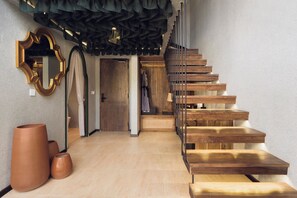 A staircase with wooden steps and a metal railing, leading to a room with a wooden door and a mirror on the wall. - Palmea Villa Seminyak by Ini Vie Hospitality (Seminyak)