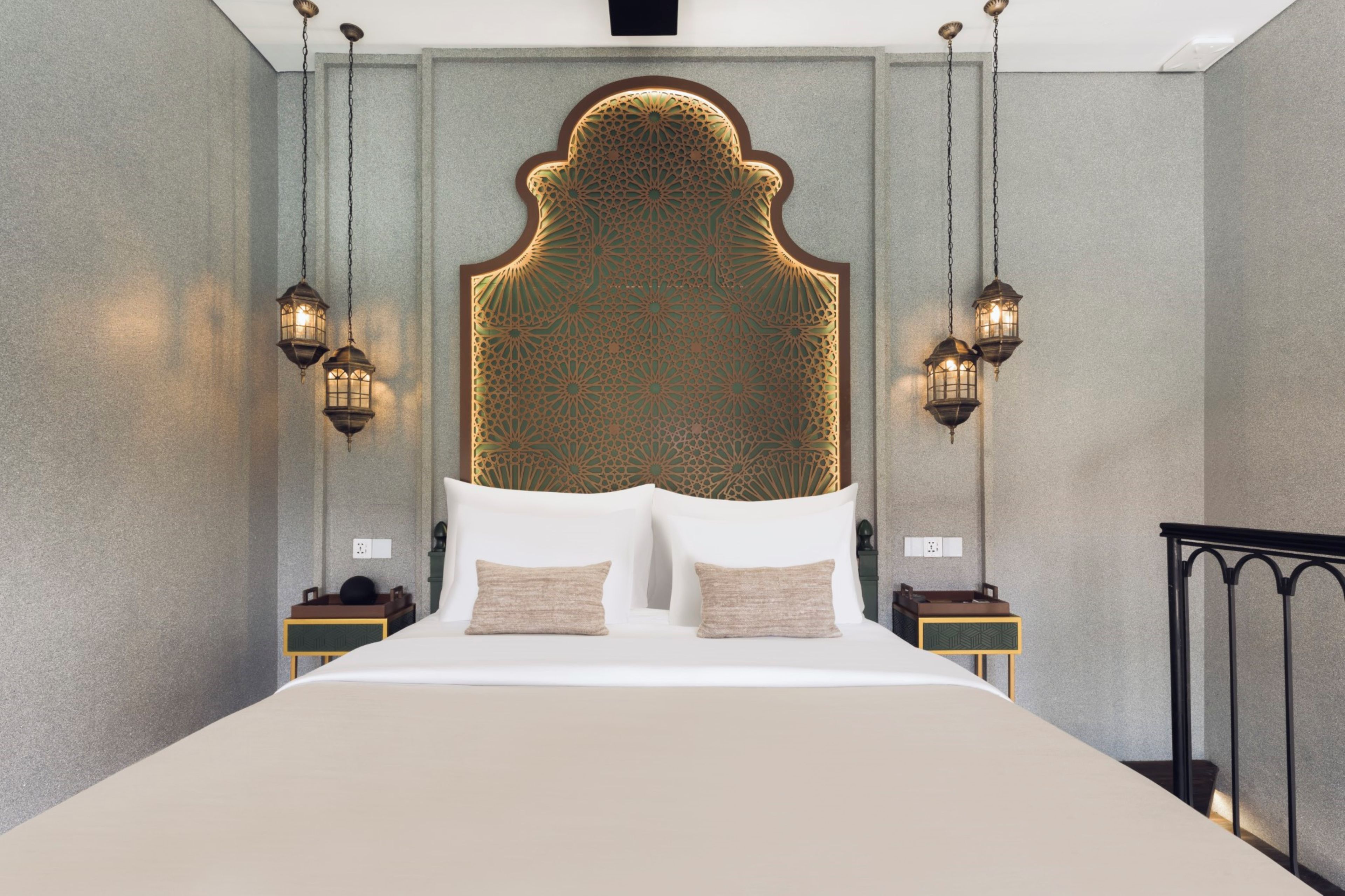 A modern bedroom with a large bed, two bedside tables, and two wall-mounted lamps.