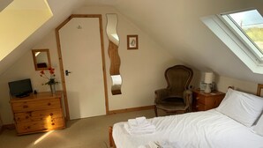 A bedroom with a bed, a chair, a dresser, a desk with a lamp, and a window. - House - Sleeps 8, Close to Beach & Free Parking (Helston)
