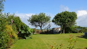 A grassy yard with trees and a small shed. - House - Sleeps 8, Close to Beach & Free Parking (Helston)