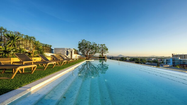 A rooftop infinity pool with lounge chairs and a view of the cityscape. - HOMA Chalong Bay (Chalong)