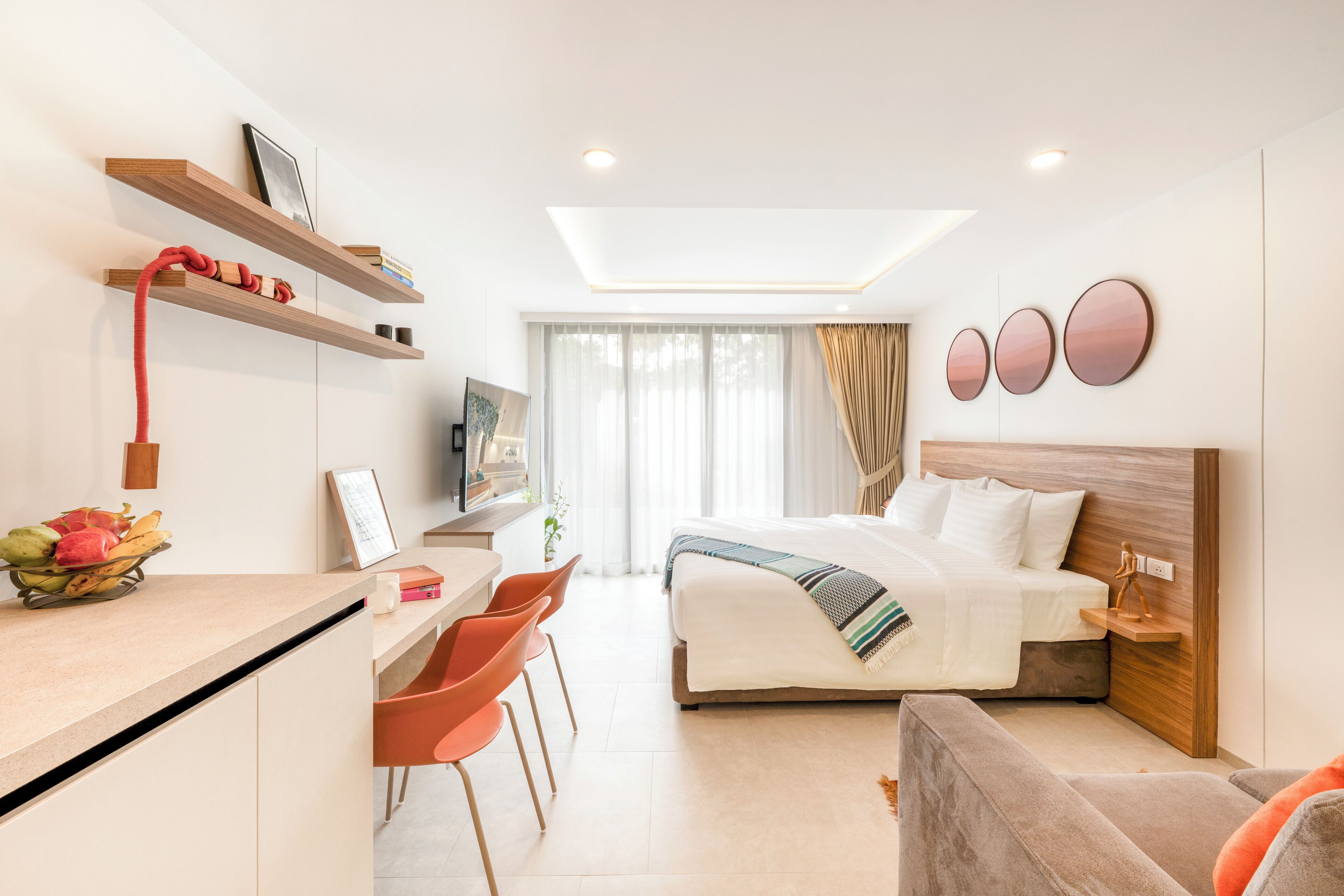 Una habitación de hotel moderna con una cama, un escritorio con sillas, un rincón de descanso y un televisor.