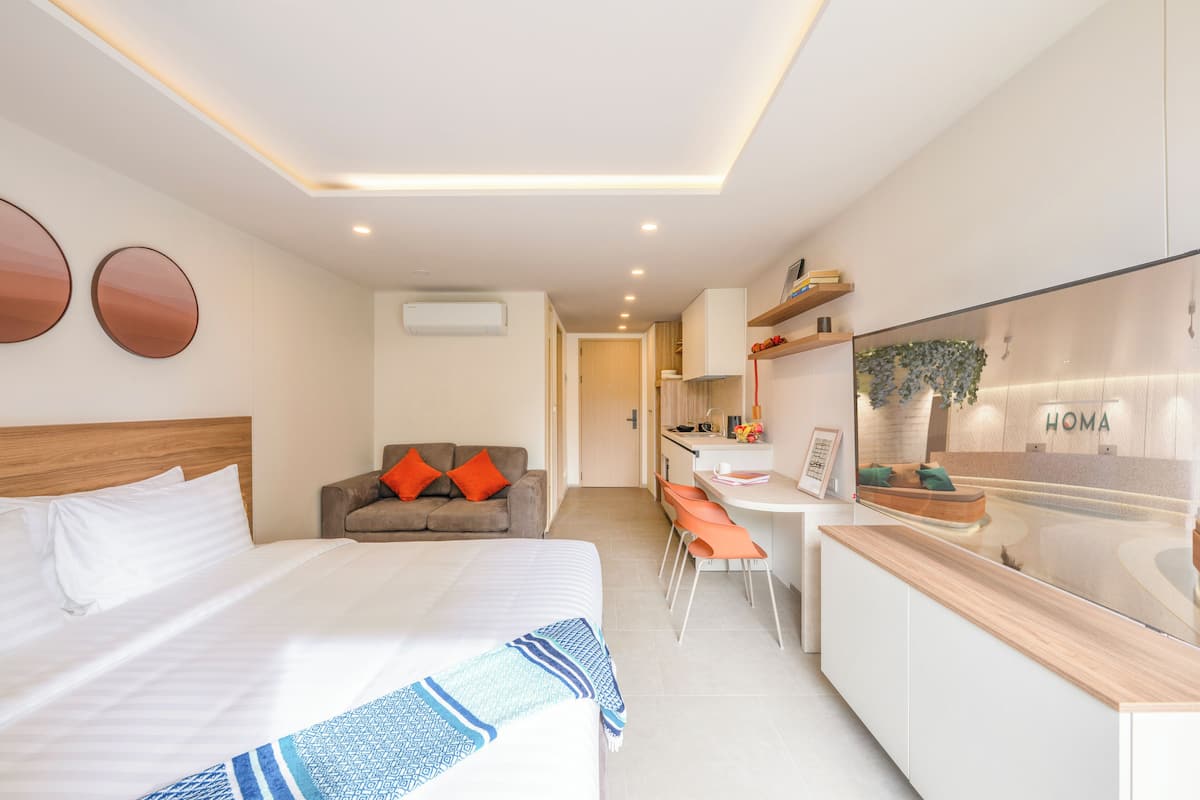 Una habitación de hotel moderna con una cama grande, un sofá, un escritorio y una kitchenette.