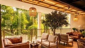 A spacious balcony with wooden flooring, leather sofas, and a large tree providing shade. - HOMA Chalong Bay (Chalong)