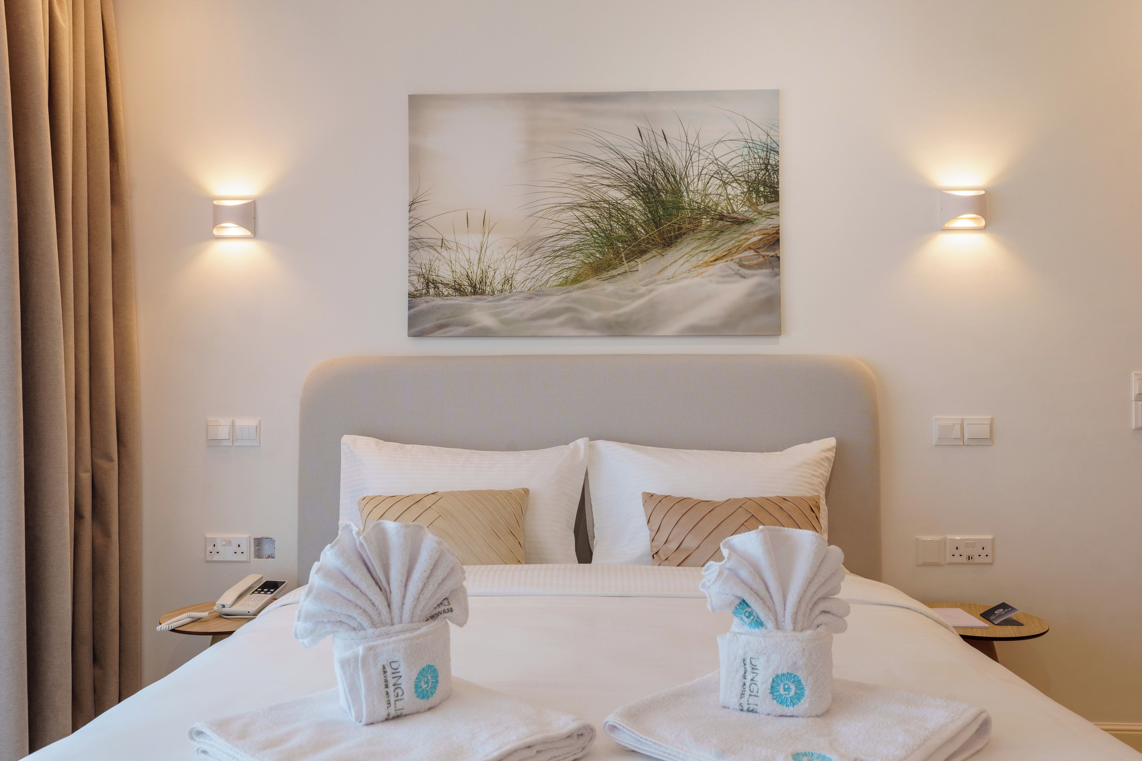 Une chambre d’hôtel avec un lit, deux tables de chevet, un tableau et des lampes fixées au mur.