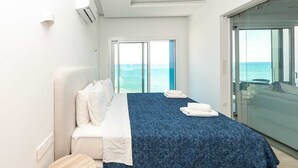 A hotel room with a bed, a large window, and a view of the sea. - Dinglis Beach Hotel Apartments (Larnaca)