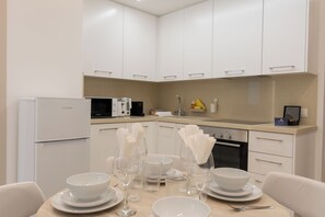 A modern kitchen with white cabinetry, a built-in oven, and a microwave. - Dinglis Beach Hotel Suites (Larnaca)