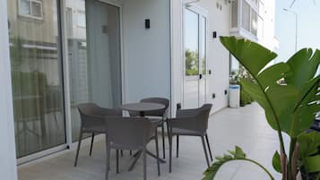 A patio with a table and chairs, a sliding glass door, and a potted plant.