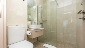 A modern bathroom with a toilet, sink, and shower. - Dinglis Beach Hotel Apartments (Larnaca)
