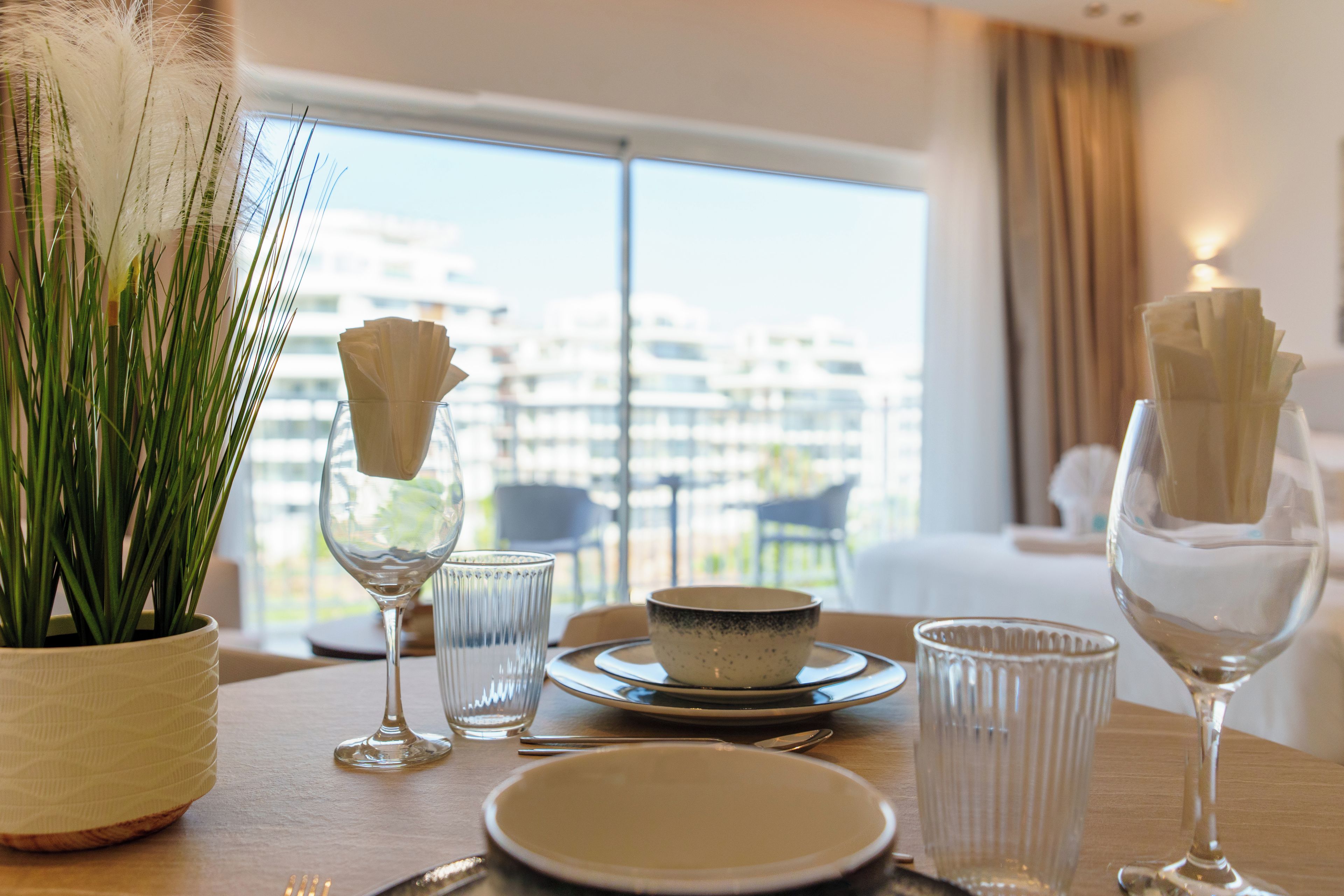 A dining table set with plates, glasses, and a vase of white flowers.