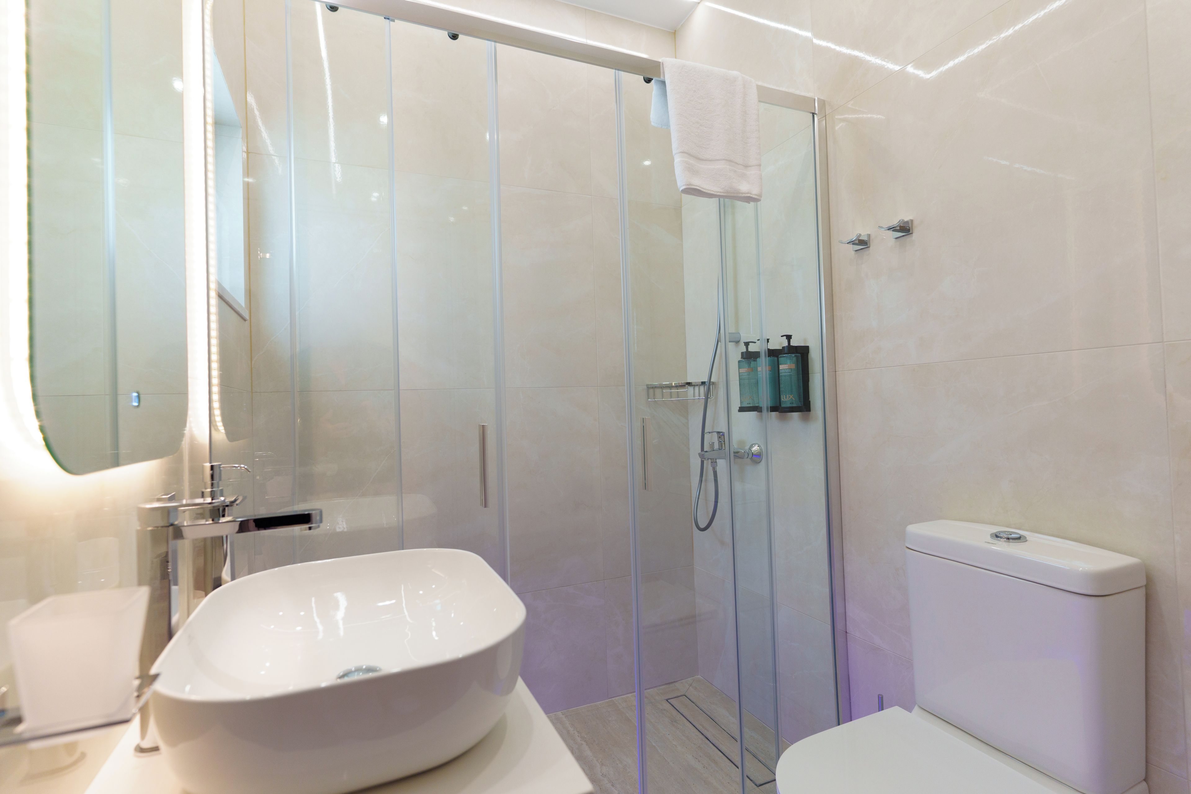 A modern bathroom with a glass-enclosed shower, a white sink, and a toilet.