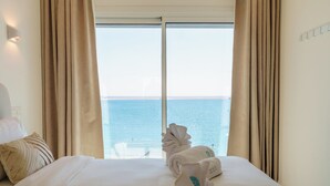 A hotel room with a large bed, beige curtains, and a view of the sea. - Dinglis Beach Hotel Apartments (Larnaca)
