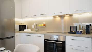Una cocina moderna con gabinetes blancos, electrodomésticos de acero inoxidable y una cafetera.