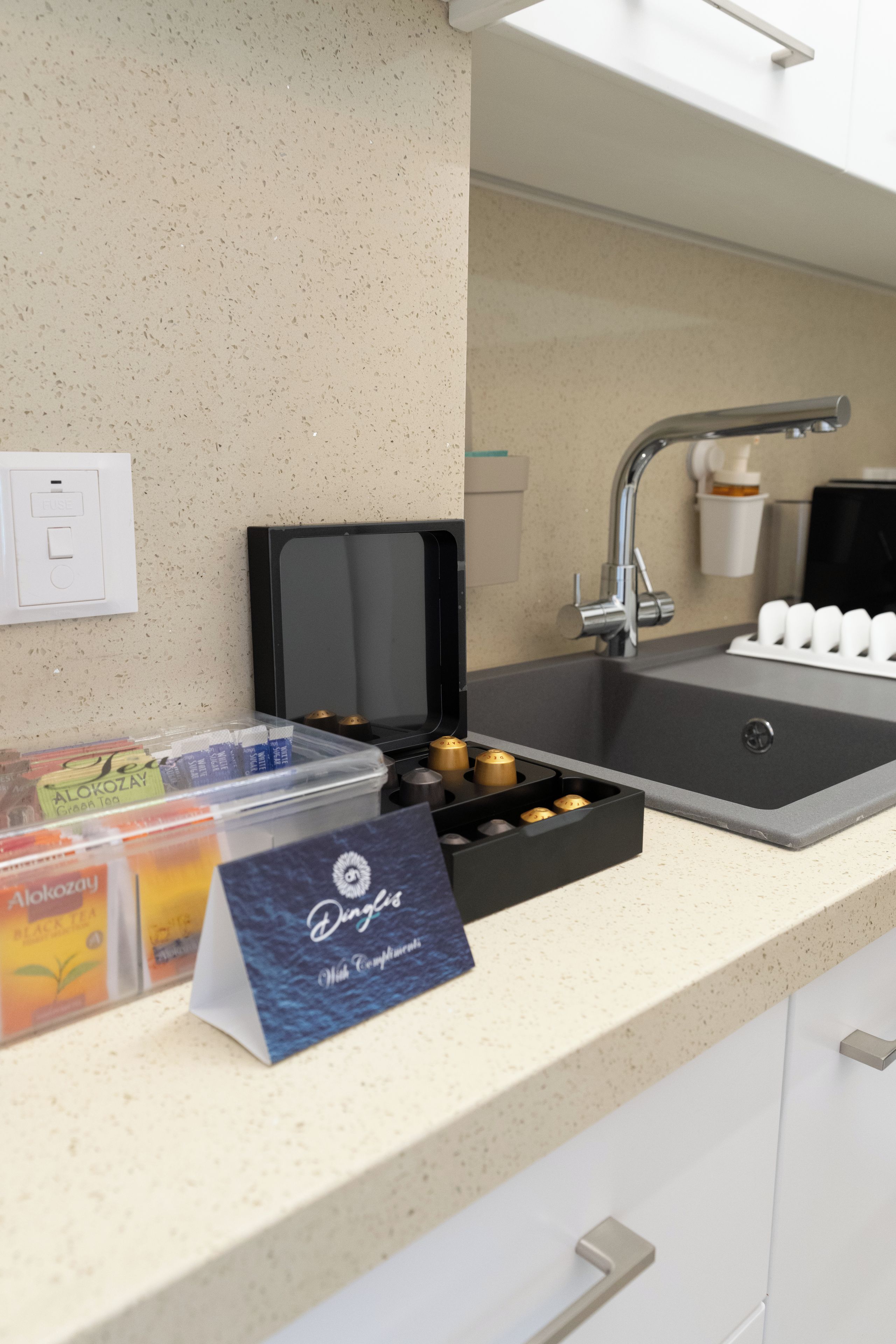 A kitchenette with a sink, a coffee machine, and a tea dispenser.