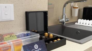 A kitchenette with a sink, a coffee machine, and a tea dispenser.