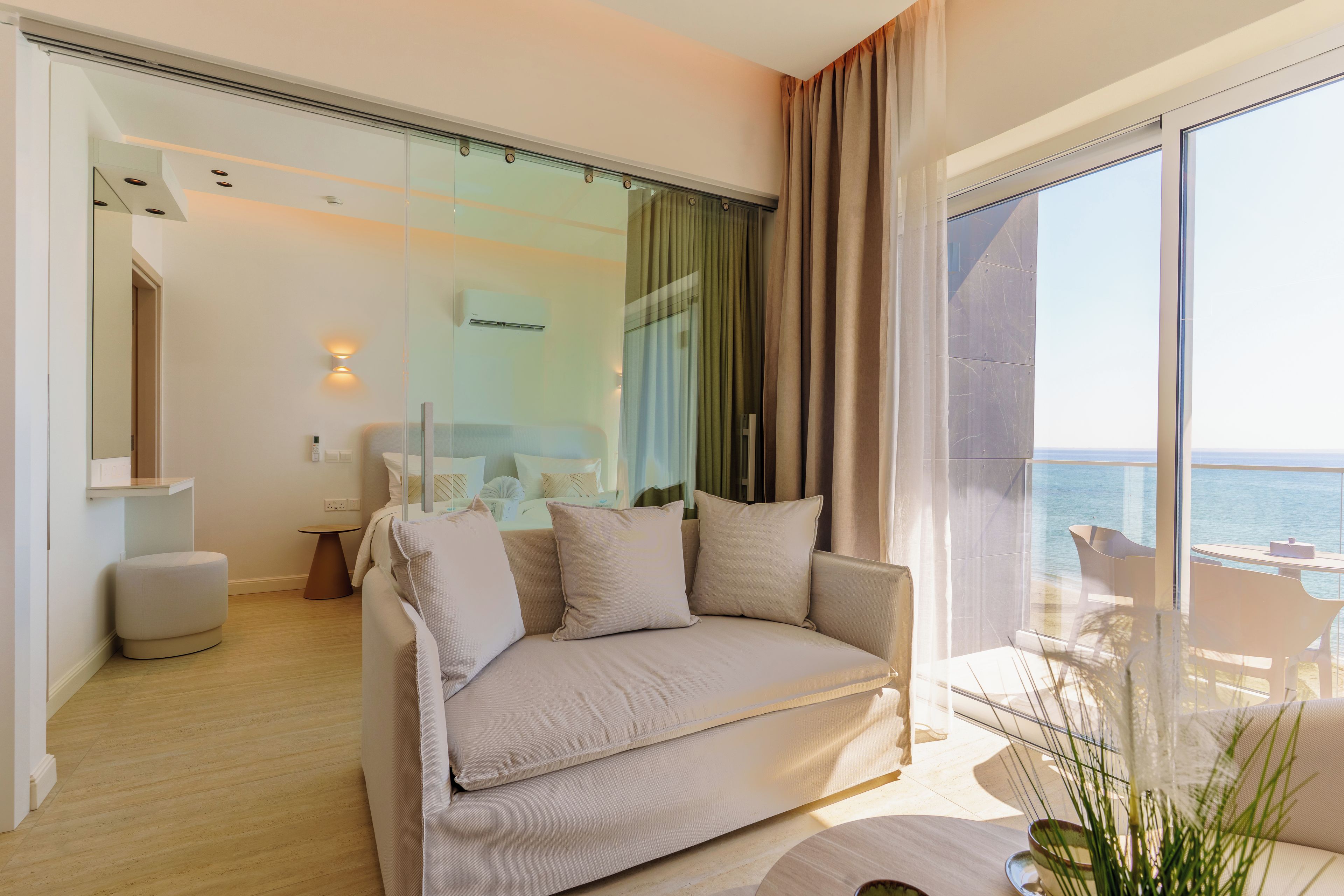 A modern living room with a sofa, a small table, and a view of the sea.