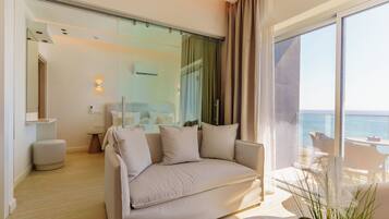 A modern living room with a sofa, a small table, and a view of the sea.
