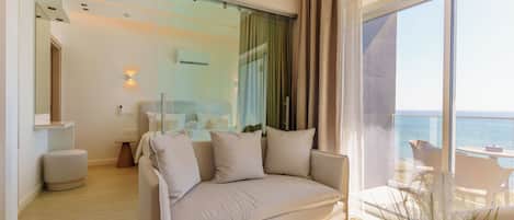 A modern living room with a sofa, a small table, and a view of the sea.