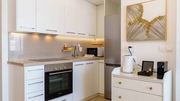 A modern kitchen with white cabinetry, a Bosch oven, a microwave, and a coffee machine.