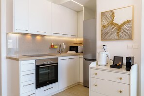 A modern kitchen with white cabinetry, a Bosch oven, a microwave, and a coffee machine. - Dinglis Beach Hotel Suites (Larnaca)